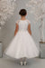 Stunning first holy communion dress has lace cap sleeves and bodice with rhinestone waist detail